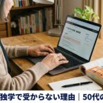 ノートパソコンの画面に向かいながら、その横にFP2級のテキストが1冊置かれている。50代女性らしき手元だけが写る構図、顔は映らない。温かみのある自然光。横長1200×630px。画像の下部に白い帯を入れて、日本語で『FP2級 独学で受からない理由|50代の気づき』とゴシック体太字の画像